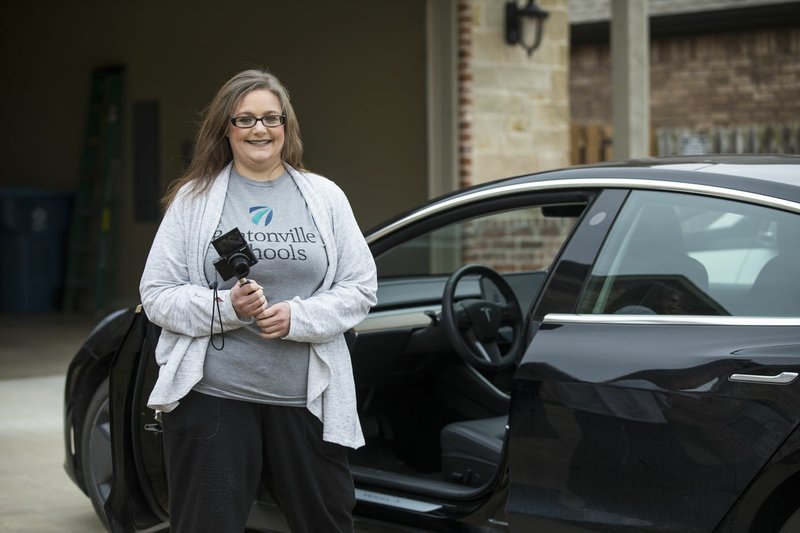 Tobie Taylor Jones, a fifth-grade science teacher at Old High Middle School, stands Friday next to her Tesla Model 3 at her home in Bentonville. Jones, like hundreds of other teachers across Northwest Arkansas, had to transition last week from teaching in her classroom to teaching from home. Go to nwaonline.com/200321Daily/ for today's photo gallery. (NWA Democrat-Gazette/Ben Goff)