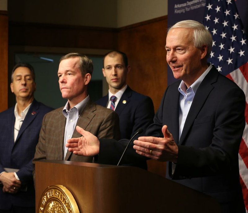 Gov. Asa Hutchinson (right) talks Sunday about the process of obtaining personal protective equipment for the state as (from left) A.J. Gary, director and state homeland security adviser; Cam Patterson, chancellor of the University of Arkansas for Medical Sciences; and Arkansas Secretary of Commerce Mike Preston listen during a news conference at the Arkansas Department of Health in Little Rock. More photos at arkansasonline.com/323covid19/. (Arkansas Democrat-Gazette/Thomas Metthe) 