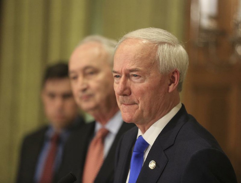 Gov. Asa Hutchinson (front), joined by Department of Finance and Administration Secretary Larry Walther and state budget administrator Jake Bleed (back), takes a question about the state budget shortfall during Monday’s news conference about the coronavirus in Arkansas. More photos at arkansasonline.com/324governor/.
(Arkansas Democrat-Gazette/Staton Breidenthal)