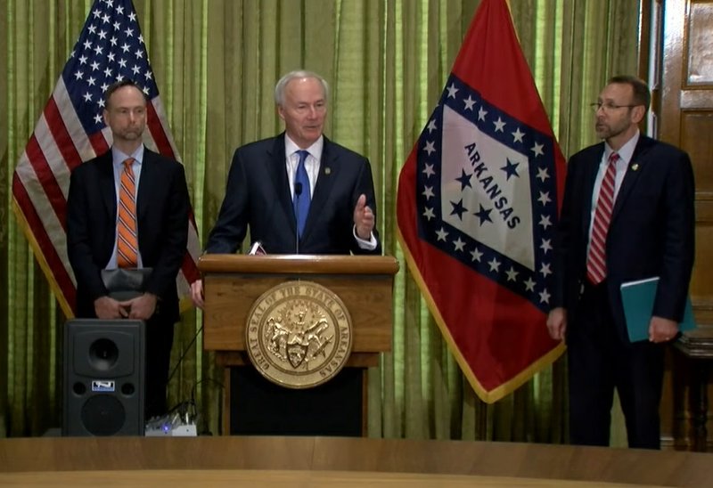 Gov. Asa Hutchinson speaks during a news conference on Monday. At left is Arkansas Surgeon General Dr. Gregory Bledsoe and at right is Health Secretary Dr. Nate Smith.