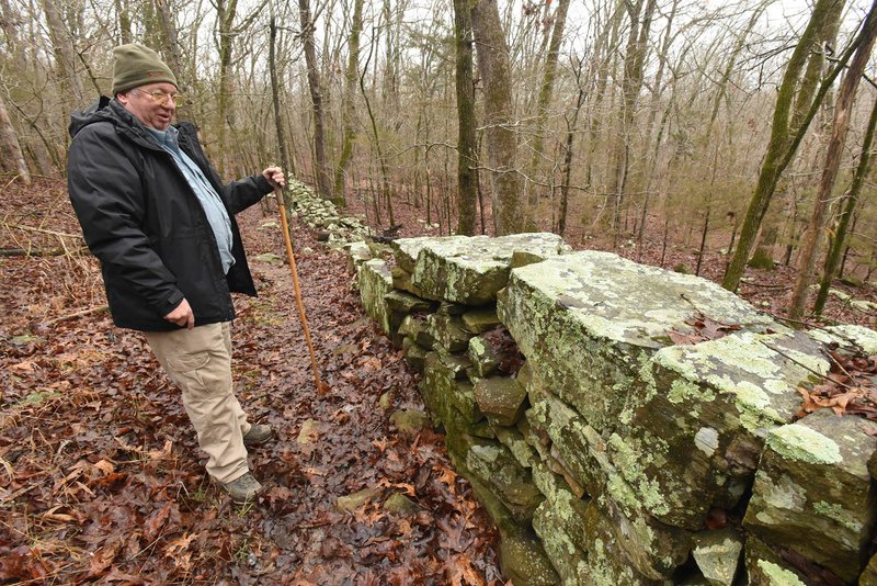 Mike McBride of Winslow hikes February 2020 along a long wall of stacked rock that runs parallel to the Rookery Trail at Lake Sequoyah in Fayetteville. The path offers a scenic hike of about 4 miles along the lake, across meadows and through woods. (NWA Democrat-Gazette/Flip Putthoff)