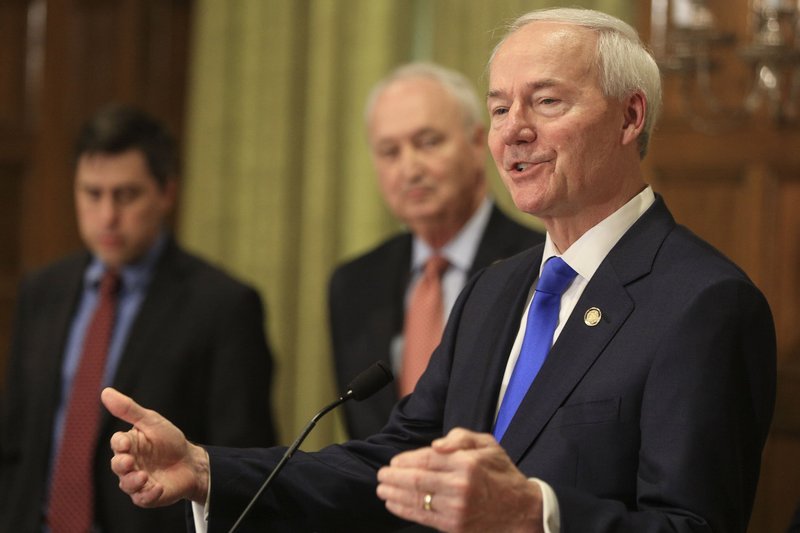 FILE - Gov. Asa Hutchinson, right, speaks along with Larry Walther, middle, Secretary of the Department of Finance and Administration and Jake Bleed, state budget director, Monday March 23, 2020 in Little Rock. 