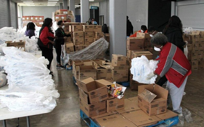 Volunteers with Delta Network Food Bank in Pine Bluff work Monday afternoon at the Pine Bluff Convention Center filling bags with chicken products donated by Tyson Foods for distribution to Arkansas residents dealing with the coronavirus pandemic crisis. About 35 volunteers helped to fill food bags, unload the truck, check people in, and hand out food to hundreds of people who showed up at the convention center in response to the food distribution event. (Arkansas Democrat-Gazette/Dale Ellis)
