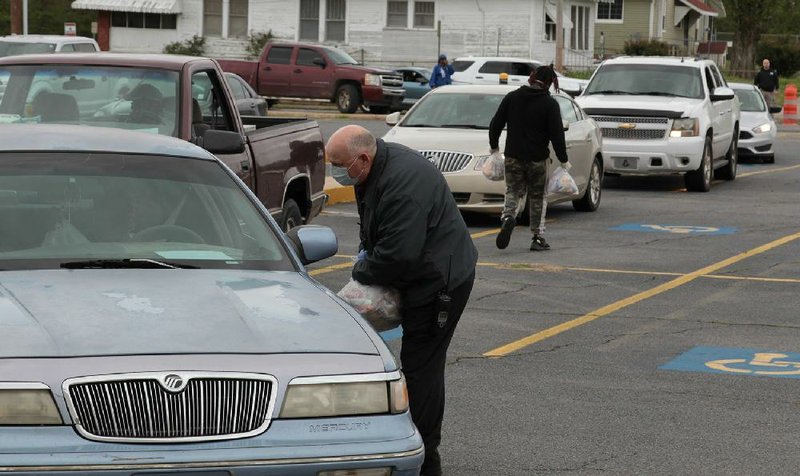 Jefferson County Deputy David Cockrell hands a bag of chicken products donated by Tyson Foods to a family outside the Pine Bluff  Convention Center during a food distribution event on March 24. More photos at arkansasonline.com/324tyson.
(Arkansas Democrat-Gazette/Dale Ellis)