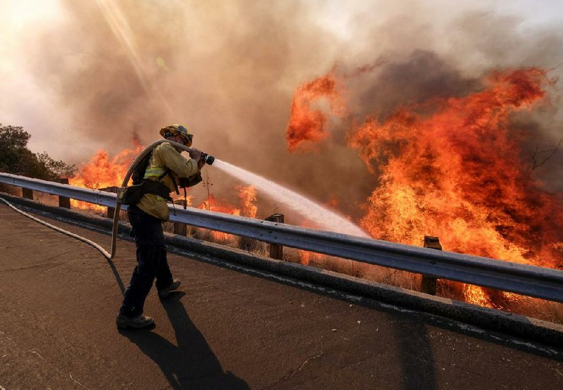 A firefighter works along California 118 in Simi Valley in 2018, the deadliest year for wildfires in California history.
(AP/Ringo H.W. Chiu)