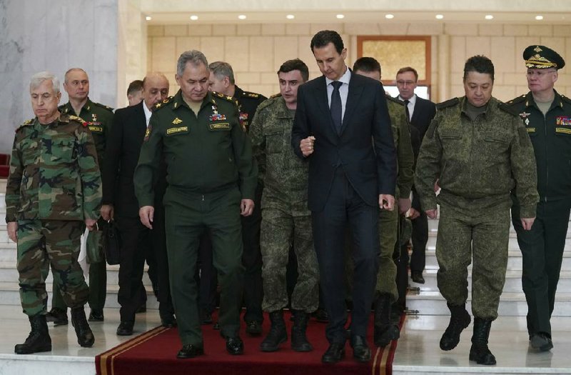 Syrian President Bashar Assad (center right) speaks with Russian Defense Minister Sergei Shoigu (center left) on Monday before their meeting in Damascus, Syria.
(SANA via AP)