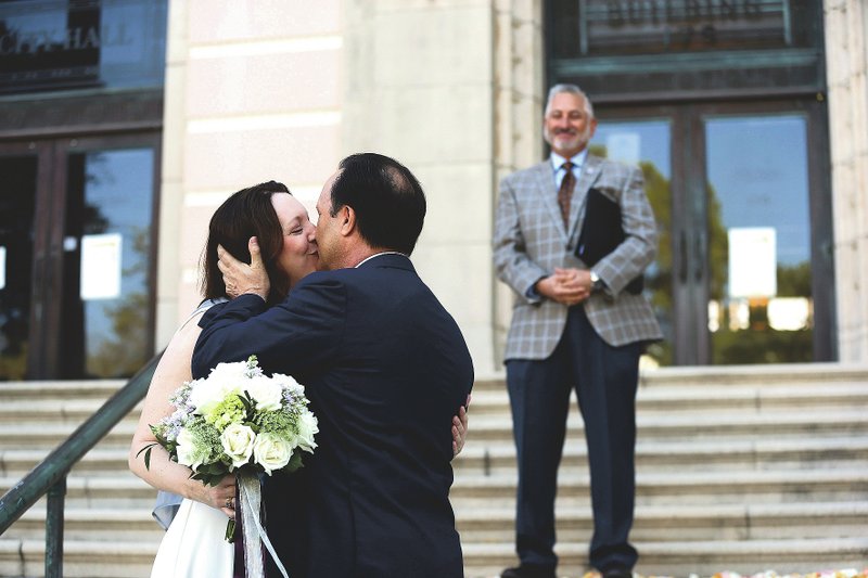 Kristen Shepherd kisses her husband Todd Berman as the couple gets married Friday on the steps of City Hall with Mayor Rick Kriseman officiating in St. Petersburg, Fla. The coronavirus forced Shepherd to cancel her original wedding plans. So she contated Kriseman to see if he would officiate her marriage to Berman on the steps of City Hall, with less than 10 people in attendance and all standing 6 feet apart. (Tampa Bay Times/Dirk Shadd)