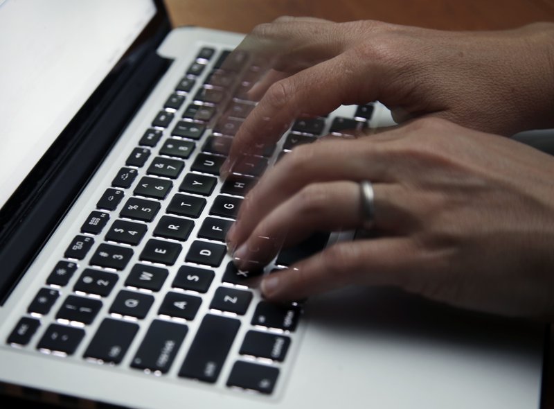 FILE - This June 19, 2017 file photo shows a person working on a laptop in North Andover, Mass. Many now are working and studying from home to limit the spread of the new coronavirus, one that's testing how productive people can be in a pandemic. It's also challenging the capacity of the internet, home Wi-Fi systems and video-chat services amid unprecedented demand. (AP Photo/Elise Amendola, File) story.lead_photo.caption