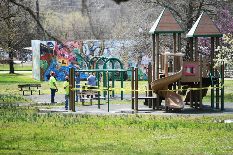 Fayetteville Parks and Recreation Department employees tape off playground equipment and dismantle swing sets Tuesday at Walker Park. The city is closing all playgrounds, sports parks, restrooms, basketball courts and water fountains as a means to prevent the spread of covid-19. Go to nwaonline.com/200325Daily/ for more photos. (NWA Democrat-Gazette/J.T. Wampler)