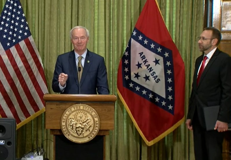 Gov. Asa Hutchinson speaks on Wednesday as Health Secretary Dr. Nate Smith looks on.