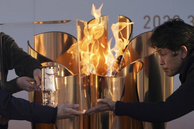 Officials light a lantern from the Olympic Flame at the end of a flame display ceremony in Iwaki, northern Japan, Wednesday, March 25, 2020. (AP Photo/Eugene Hoshiko)