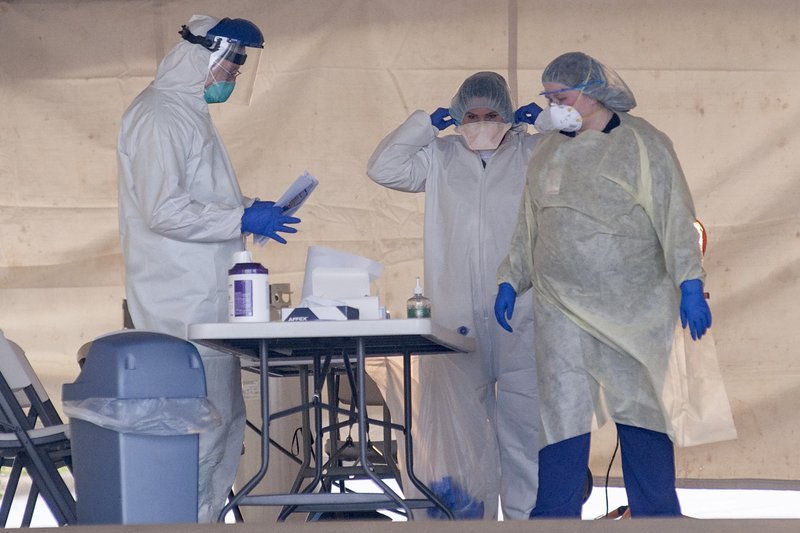 Healthcare professionals wear personal protective equipment as they prepare to test patients for flu, strep throat, and coronavirus from their parked cars on Tuesday, March 24, 2020, at the St. Bernards Urgent Care Clinic on Red Wolf Boulevard in Jonesboro, Ark. (Quentin Winstine/The Jonesboro Sun via AP)