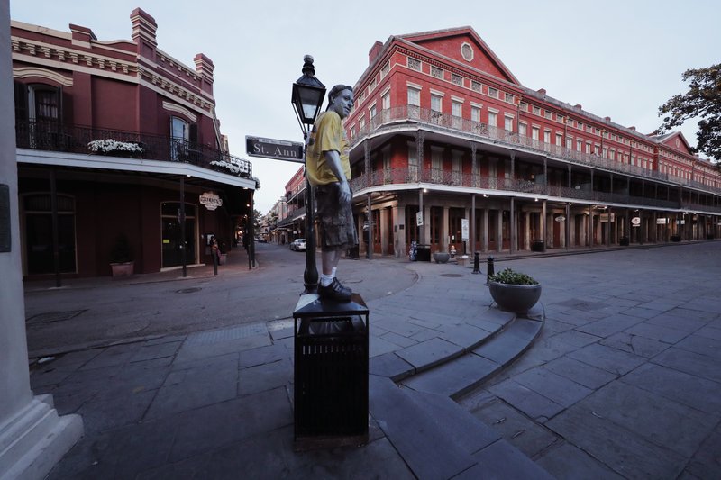 In this Sunday, March 22, 2020, file photo, street performer Eddie Webb looks around the nearly deserted French Quarter looking to make money in New Orleans. Like many cities around the country, New Orleans is currently under a shelter-in-place order as it grapples with a growing number of coronavirus cases. Louisiana Gov. John Bel Edwards has repeatedly sounded the alarm about how Louisiana has the third-highest rate of confirmed virus cases per capita while at the same time noting the difficulty of the small state getting supplies. (AP Photo/Gerald Herbert, File)