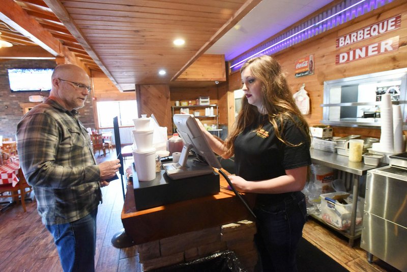 Chris Kauffman picks up a take-out order on Tuesday March 24 2020 from employee Debra Patton at Smokin' Joe's Ribhouse in Rogers. Go to nwaonline.com/200325Daily/ to see more photos.
(NWA Democrat-Gazette/Flip Putthoff)