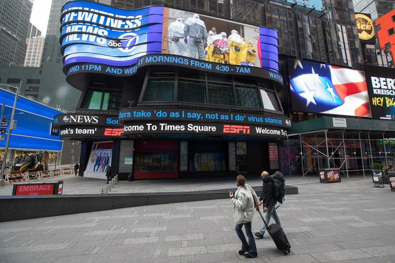 A couple looks at the ABC News video screen showing coverage of a coronavirus outbreak in Woodbridge, N.J., Wednesday, March 25, 2020, in New York's Times Square. The number of people hospitalized with COVID-19 in New York climbed to 3,800, with close to 900 in intensive care, with the peak of the outbreak weeks away, Gov. Andrew Cuomo said Wednesday. The Arkansas Department of Health on Thursday recommended anyone that anyone who has recently traveled to New York state or internationally to quarantine themselves at home for 14 days. (AP Photo/Mary Altaffer)