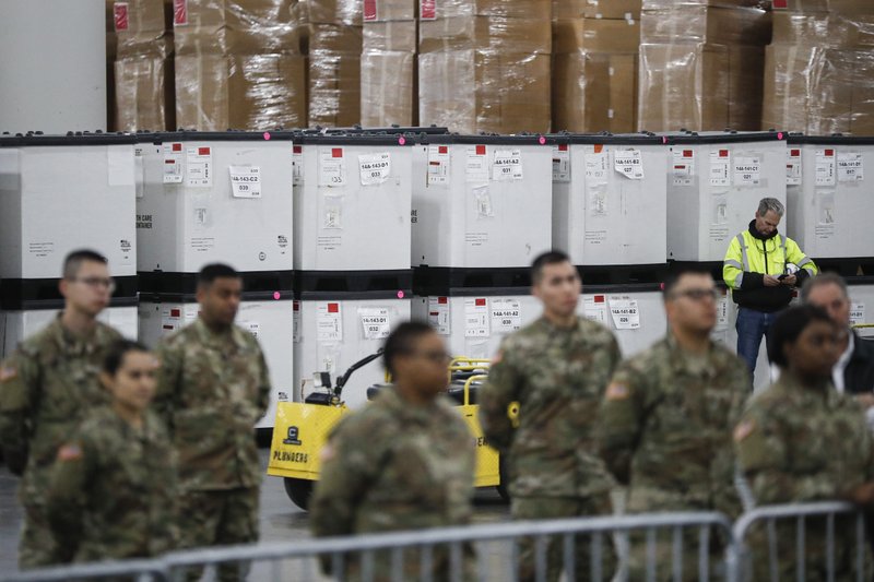 U.S. National Guard members stand beside crates of medical supplies at the Jacob Javits Center, Monday, March 23, 2020, in New York. New York City hospitals are just 10 days from running out of "really basic supplies" Mayor Bill de Blasio said late Sunday. De Blasio has called upon the federal government to boost the city's quickly dwindling supply of protective equipment. The city also faces a potentially deadly dearth of ventilators to treat those infected by the coronavirus. (AP Photo/John Minchillo)