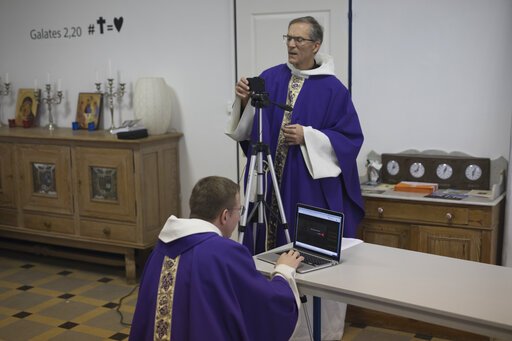 Priest Philippe Rochas, left, and Jean-Benoit de Beauchene pack up livestreaming equipment after holding a closed-door Sunday Mass at the St. Vincent de Paul church in Marseille, southern France, on March 22. As mass gatherings are forbidden due to measures to prevent the spread of COVID- 19, priests are using technology to reach worshippers forced to stay at home. For most people, the new coronavirus causes only mild or moderate symptoms. - AP Photo/Daniel Cole