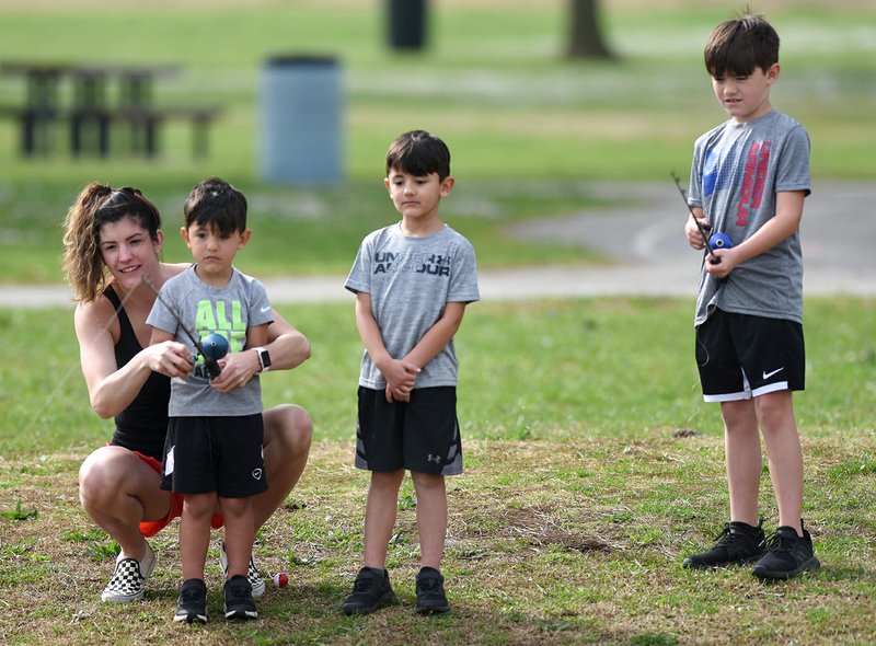 Jessica Martinez (from left) fishes Friday with her sons Samuel, 4, Matthew, 5, and Jakob, 9, at Murphy Park in Springdale. The Arkansas Game and Fish Commission, in cooperation with Gov. Asa Hutchinson, waived all fishing license and trout permit requirements for residents and nonresidents for the week ending at 11:59 p.m Sunday. (NWA Democrat-Gazette/David Gottschalk)