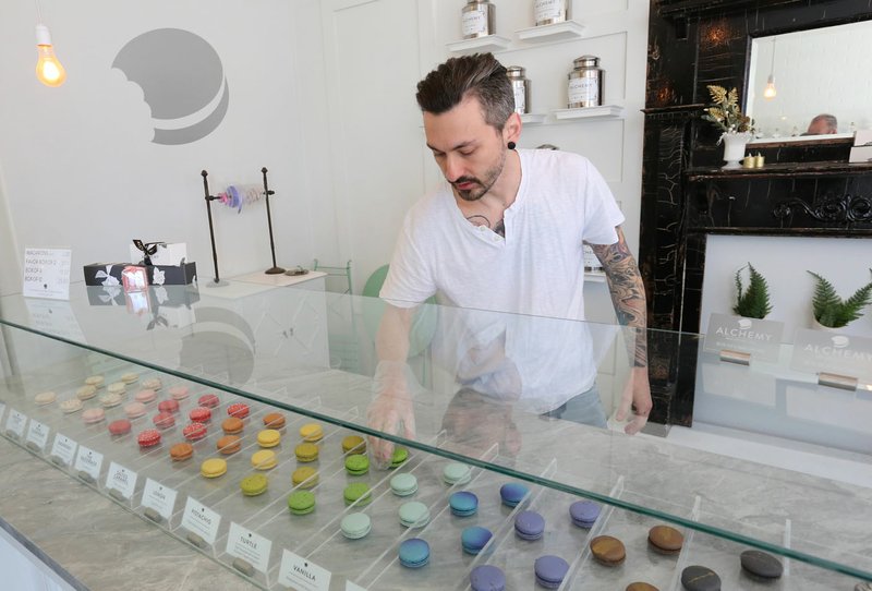 Oliver Crumpton arranges macarons in the display case Tuesday in his store, Alchemy Macarons on Center Street in downtown Fayetteville. The small business is continuing to stay open to keep workers employed. Go to nwadg.com/photos for a photo gallery. (NWA Democrat-Gazette/David Gottschalk)