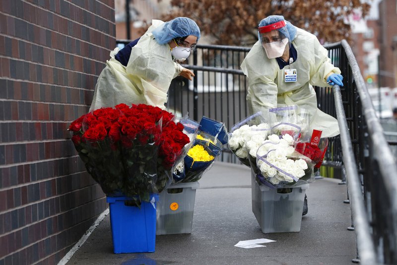 Emergency room nurses transport buckets of donated flowers up a ramp outside Elmhurst Hospital Center's emergency room, Saturday, March 28, 2020, in New York. The hospital has been heavily taxed by treating an influx of coronavirus patients during the current viral pandemic. Currently, New York leads the nation in the number of cases, according to Johns Hopkins University, which is keeping a running tally. (AP Photo/Kathy Willens)