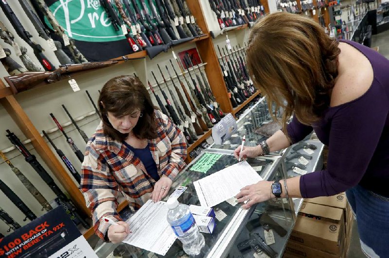 Andrea Schry (right) fills out legal forms to buy a handgun as shop worker Missy Morosky fills out the vendor forms after Dukes Sport Shop in New Castle, Pa., reopened this week under the new conditions specified for gun stores.
(AP/Keith Srakocic)