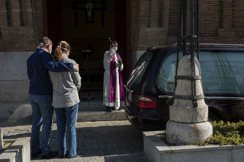 Mourners keep their distance Friday as a priest performs funeral rites at a cemetery in Madrid. The number of deaths from the coronavirus has climbed past 4,900 in Spain, second only to Italy. More photos at arkansasonline.com/328outbreak/.
(AP/Bernat Armangue)
