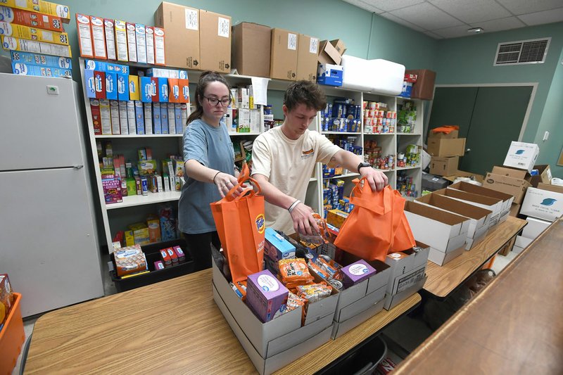 Cecelia Johnson (left) and Russ Johnson, both of Fayetteville, pack food boxes March 16 at the Fayetteville Public Schools food pantry called The Outback located at the ALLPS School of Innovation at 2350 Old Farmington Road. The Outback is one of the organizations that will benefit from the Fayetteville Public Education Foundation covid-19 Family Relief Fund. (NWA Democrat-Gazette/J.T. Wampler)