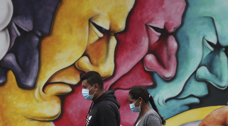 People walk past a mural Saturday in Quito, Ecuador, where the government has declared a health emergency, enacting a curfew and restricting movement to only those who provide basic services. More photos at arkansasonline.com/329pandemic/.
(AP/Dolores Ochoa)