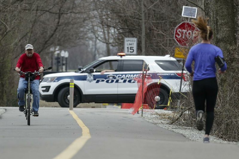 Police block a section of a trail in Carmel, Ind., on Thursday. In big cities and remote areas alike, officers are being told to issue tickets or summons rather than making arrests for minor crimes as law enforcement agencies try to limit exposure to the coronavirus.
(AP/Michael Conroy)