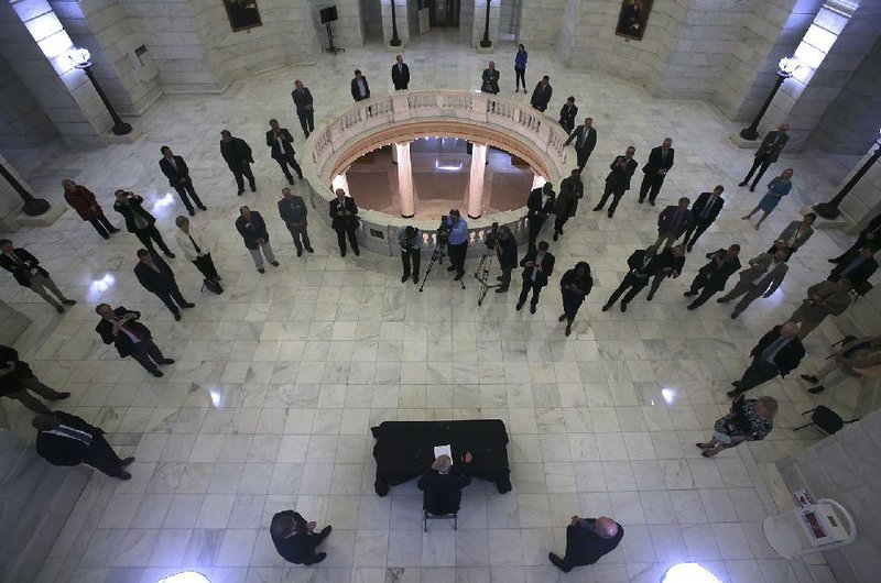 Arkansas Gov. Asa Hutchinson (bottom center), surrounded by members of the General Assembly, signs emergency legislation early Saturday in the rotunda of the state Capitol in Little Rock. More photos at arkansasonline.com/329midnight/.
(Arkansas Democrat-Gazette/Thomas Metthe)