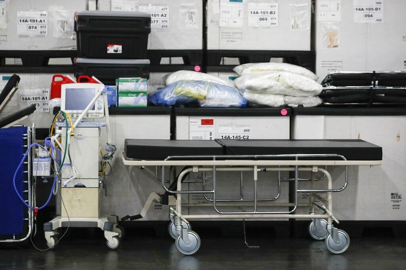 FILE - This Monday, March 23, 2020, file photo shows medical supplies and a stretcher displayed before a news conference at the Jacob Javits Center in New York. Health care workers are dreading the prospect of deciding which patients would get a ventilator that could save their lives. (AP Photo/John Minchillo, Fle)