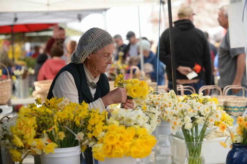 Janet Bachmann, owner of Riverbend Gardens in Fayetteville, creates bouquets April 6 during the Fayetteville Farmers Market at the city's downtown square. The market's opening day will be postponed this year because of the covid-19 pandemic. (File photo/NWA Democrat-Gazette/Andy Shupe)