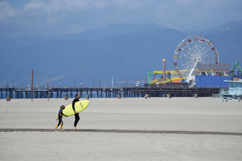 A surfer walks with a child Sunday on the mostly empty Santa Monica beach in Los Angeles County, Calif.
(AP/Marcio Jose Sanchez)