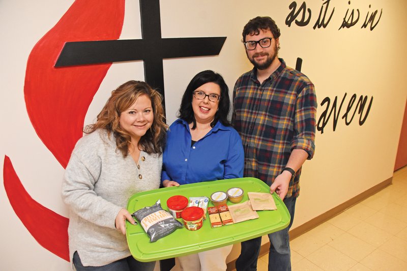 Staff members of First United Methodist Church in Maumelle display some of the items sent home to area students as part of the church’s Backpack Ministry. From left are Kayla Tullos, children’s director; the Rev. Aubrietta Jones, senior pastor; and Nick Garrison, youth director.