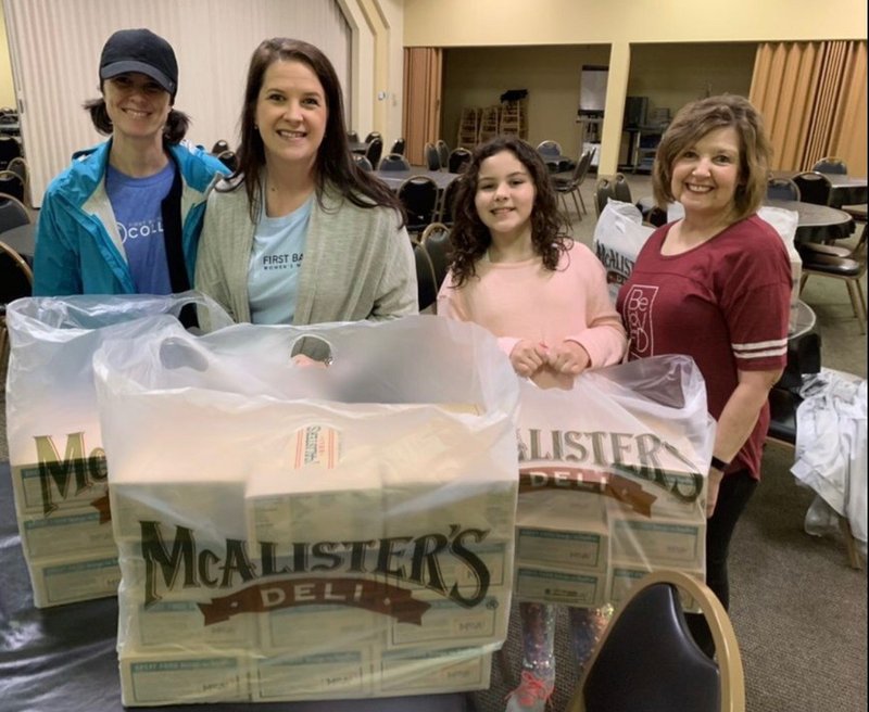 From left, volunteers Melissa Rogers, Brooke Ramsey, Eva Ramsey and Nancy Cummings help package and distribute donated food from McAlister’s Deli in Russellville. The food was distributed to area first responders and the River Valley Food 4 Kids food bank