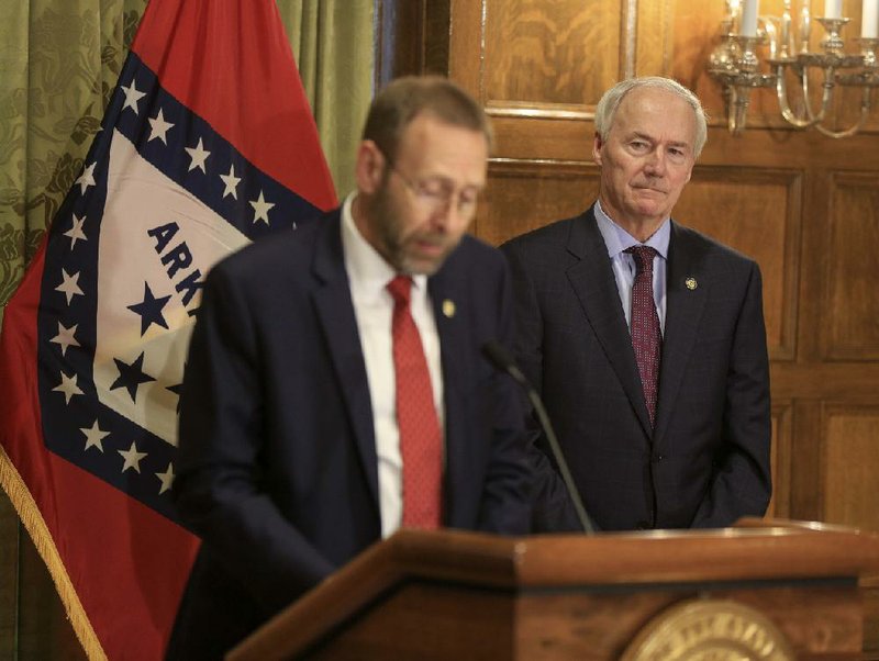Gov. Asa Hutchinson, right, listens as Health Secretary Dr. Nate Smith speaks Monday March 30, 2020 in Little Rock during a daily press conference about the corona virus in Arkansas. See more photos at arkansasonline.com/331governor/.

