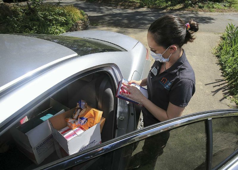 Dayna Casas, quality care manager with Right at Home, gets ready to put on a pair of gloves Wednesday before seeing a client in Little Rock. (Arkansas Democrat-Gazette/Staton Breidenthal) 
