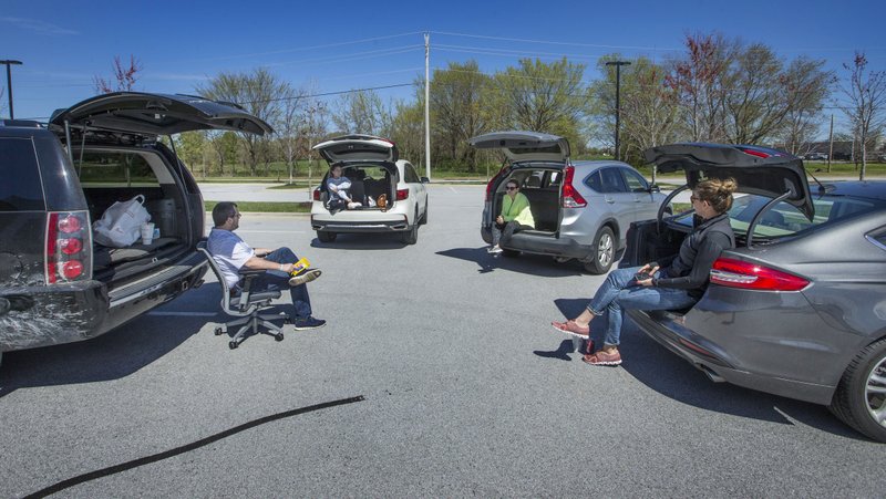 Tripp Hollowell (from left), Shannon Suttie, Ginger Macfarlan and Lindsay Letterle hold a team meeting Wednesday, March 25, 2020, in the parking lot at The Clorox Co. office in Bentonville. They'd been working from home and wanted to take advantage of the nice weather. People are coming up with creative ways to socialize from a distance.

(NWA Democrat-Gazette/Ben Goff)