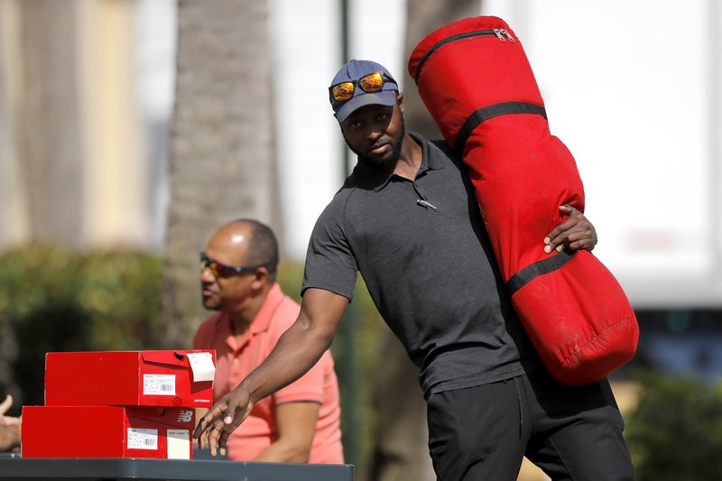 St. Louis Cardinals minor league outfielder Bradley Roper-Hubbert carries gear as he leaves the team's spring training baseball clubhouse, Friday, March 13, 2020, in Jupiter, Fla. Major League Baseball has delayed the start of its season by at least two weeks because of the coronavirus outbreak as well as suspended the rest of its spring training game schedule. (AP Photo/Julio Cortez)