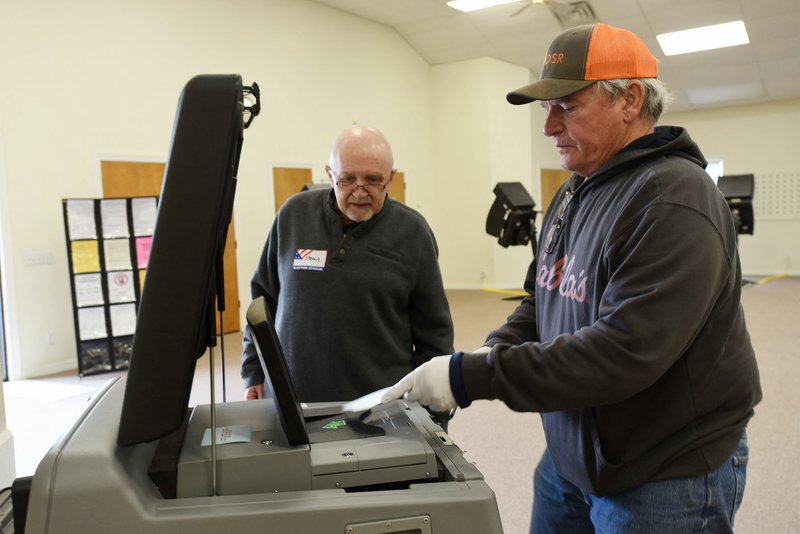 Steven Jarnagan (left), poll worker, helps Frank Klimek of Bethel Heights cast his ballot Tuesday at First Baptist Church in Lowell. Go to nwaonline.com/200401Daily/ to see more photos. (NWA Democrat-Gazette/Flip Putthoff)