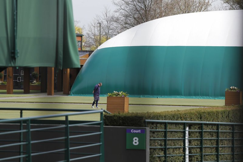 A groundsman looks at the grass on one of the outside courts at Wimbledon as it is announced the the Wimbledon tennis Championships for 2020 has been cancelled due to the coronavirus in London, Wednesday, April 1, 2020. The new coronavirus causes mild or moderate symptoms for most people, but for some, especially older adults and people with existing health problems, it can cause more severe illness or death.(AP Photo/Kirsty Wigglesworth)