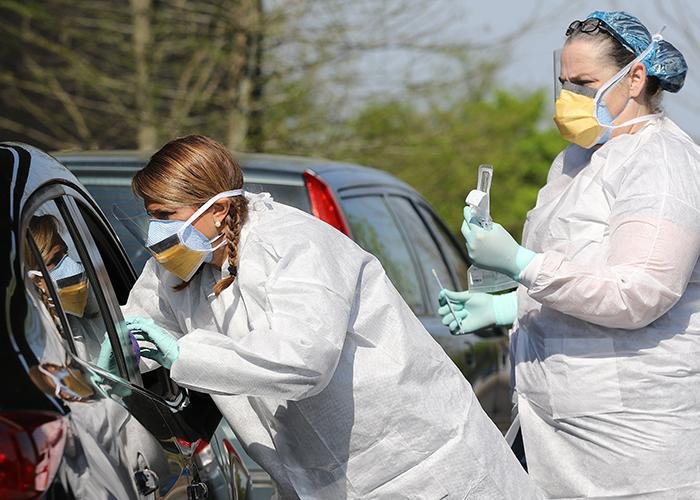 Nurses Mandy Stuckey (left) and Tonya Green conduct a coronavirus screening in April at a drive-thru site at New Life Church in North Little Rock. The site, and one at Ouachita Baptist Universityin Arkadelphia, is a partnership between two Arkansas companies. (Arkansas Democrat-Gazette/Thomas Metthe)