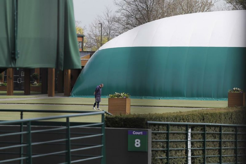 A groundsman examines the grass on one of the outside courts at Wimbledon. It was announced Wednesday that the tournament in London is canceled.
(AP/Kirsty Wigglesworth)