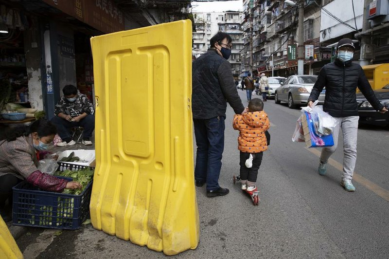 Vendors prepare vegetables behind barriers Wednesday in a Wuhan neighborhood in central China.
(AP/Ng Han Guan)