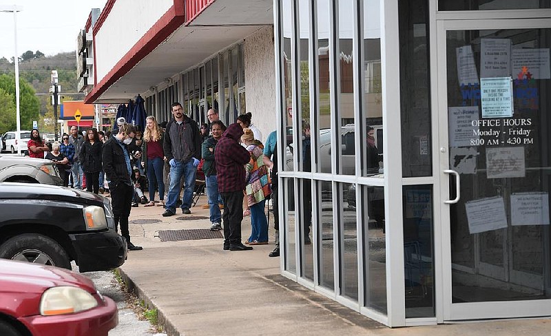 A line of around 50 people extends from the door of Arkansas Workforce Center, Monday, March 30, 2020, in Fayetteville. (NWA Democrat-Gazette/J.T. Wampler)