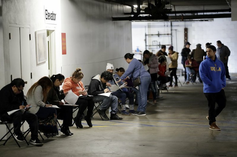 In this March 13, 2020 file photo, unionized hospitality workers wait in line in a basement garage to apply for unemployment benefits at the Hospitality Training Academy in Los Angeles. More than 6.6 million Americans applied for unemployment benefits last week, far exceeding a record high set just last week, a sign that layoffs are accelerating in the midst of the coronavirus. (AP Photo/Marcio Jose Sanchez, File)