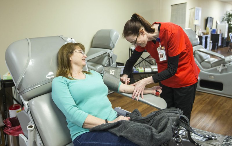 Julie Jones (right), donor specialist, prepares Lisa Craig of Avoca, a regular donor for the past two decades, for a donation recently at the Community Blood Center of the Ozarks donor center in Bentonville. CBCO employee Christopher Pilgrim says the organization is in danger of experiencing a shortage in donations due to recent blood drive cancellations as a result of the covid-19 outbreak. (NWA Democrat-Gazette/Ben Goff)