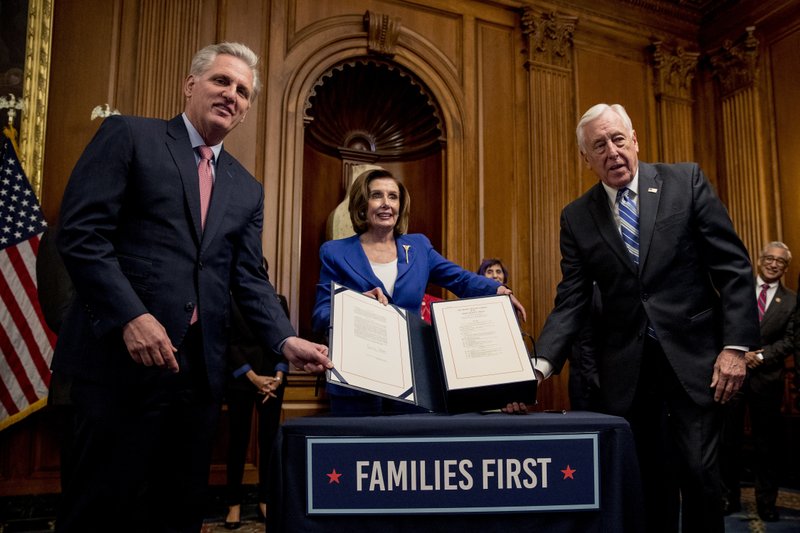 House Speaker Nancy Pelosi of Calif., House Minority Leader Kevin McCarthy of Calif., left, and House Majority Leader Steny Hoyer of Md., right, holds up the Coronavirus Aid, Relief, and Economic Security (CARES) Act after Pelosi signed it on Capitol Hill, Friday, March 27, 2020, in Washington. The $2.2 trillion package will head to head to President Donald Trump for his signature. (AP Photo/Andrew Harnik)
