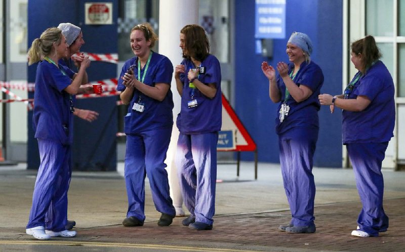 Staff members at the Royal Liverpool University Hospital in Liverpool, England, join in a national round of applause Thursday for people on the front lines in fighting the coronavirus. More photos at arkansasonline.com/43uk/.
(AP/Peter Byrne)