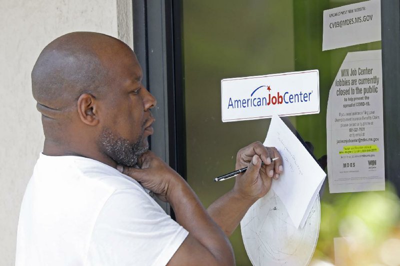 An applicant copies the link to Mississippi’s unemployment website Thursday outside a state job center office  in  Jackson.  Job  center  lobbies are  closed  statewide  to prevent  the  spread of  the coronavirus, and officials encourage applying online. Some centers have made paper applications available to those without computers for them to mail back or push through the centers’ mail slots or doors. More photos at arkansasonline.com/43jobless/.
(AP/Rogelio V. Solis)
